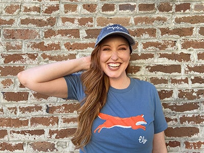 Redhead smiling in Fox T Shirt wearing an Inspire Joy hat